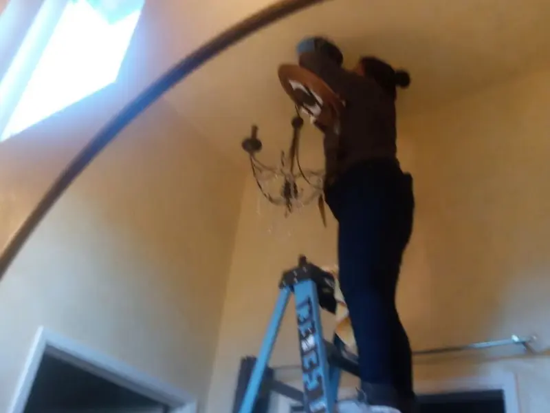 Electrician installing a chandelier in a Dundalk residence